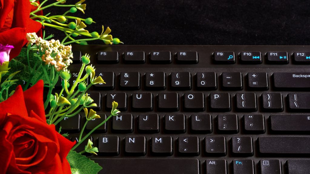 Roses and flowers in front of a black computer keyboard on a black background